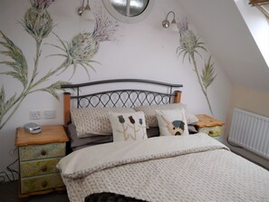 Un dormitorio con cama, dos mesitas de noche, cómoda y radiador.
