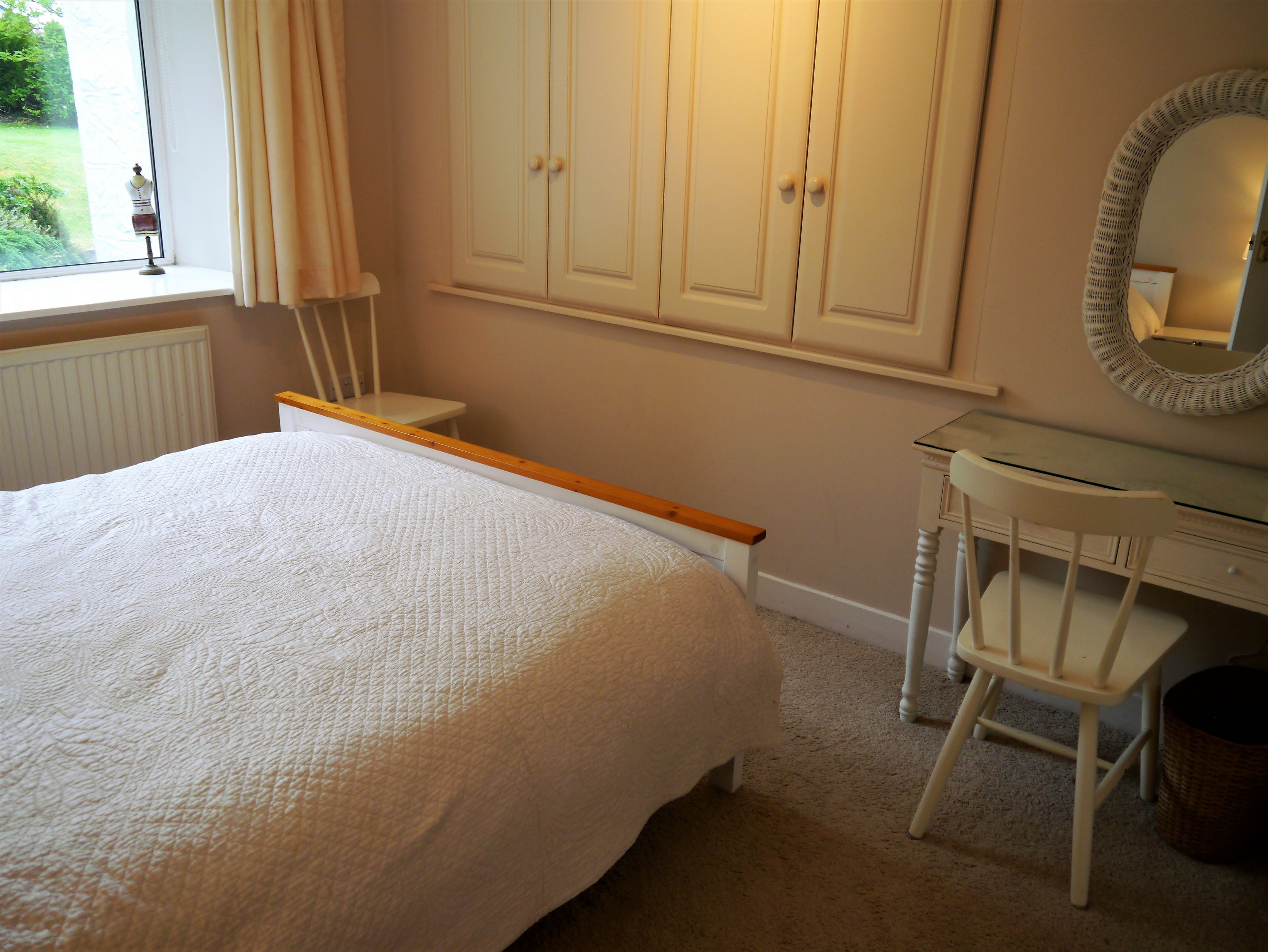 Un dormitorio con cama, escritorio, silla y armario.
