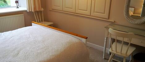 Un dormitorio con cama, escritorio, silla y armario.