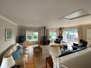 Un salon spacieux avec un canapé, des fauteuils, un téléviseur et une cheminée.