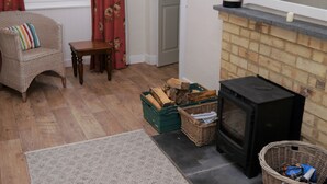 Una sala de estar acogedora con chimenea, muebles de mimbre y una ventana con cortinas.