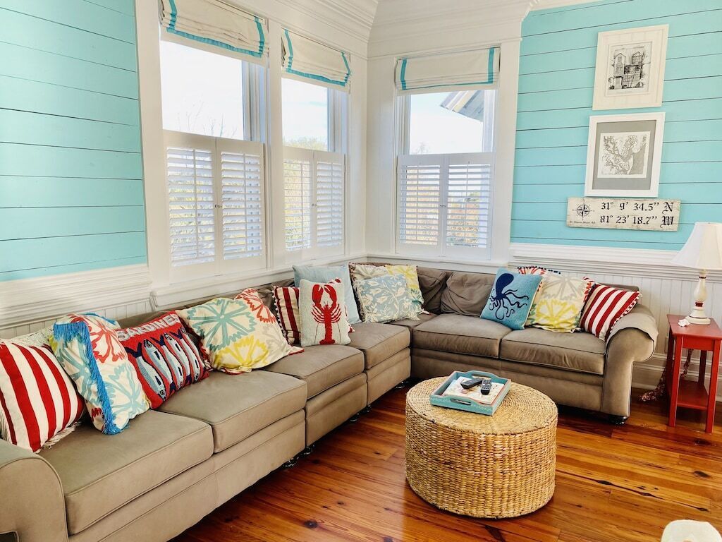 A cozy living room with a sectional sofa, a round wicker coffee table, and a small side table.