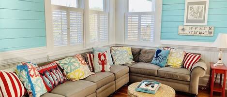 A cozy living room with a sectional sofa, a round wicker coffee table, and a small side table.