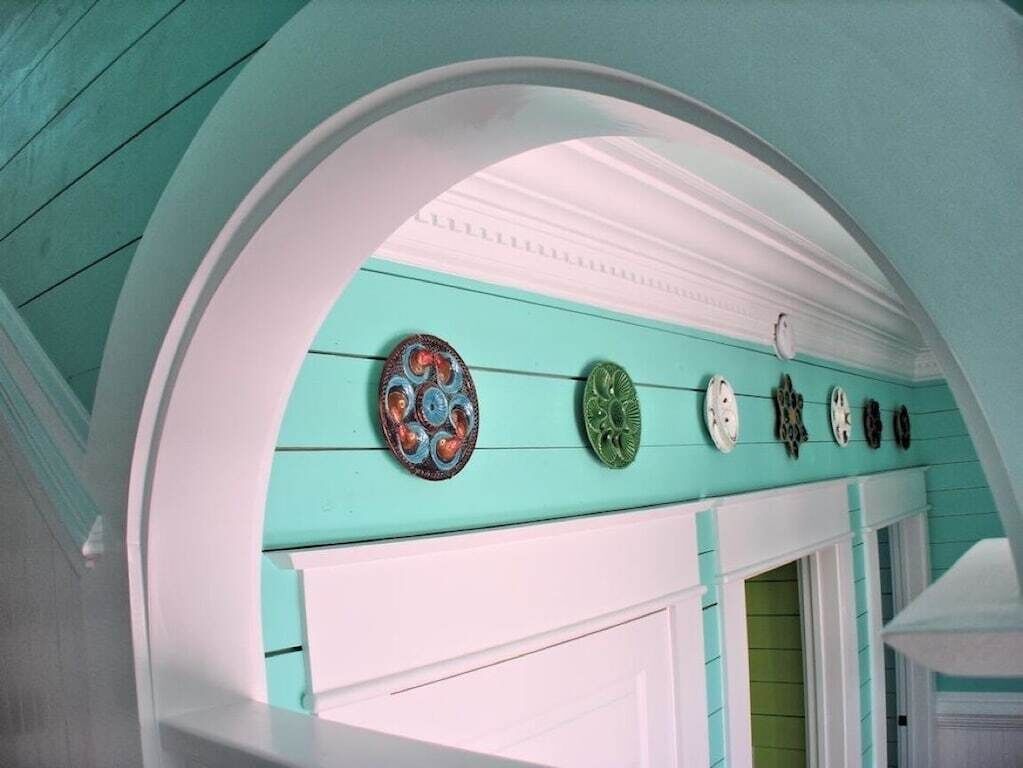 Un corridoio color turchese con una porta e una finestra dal telaio bianco.
