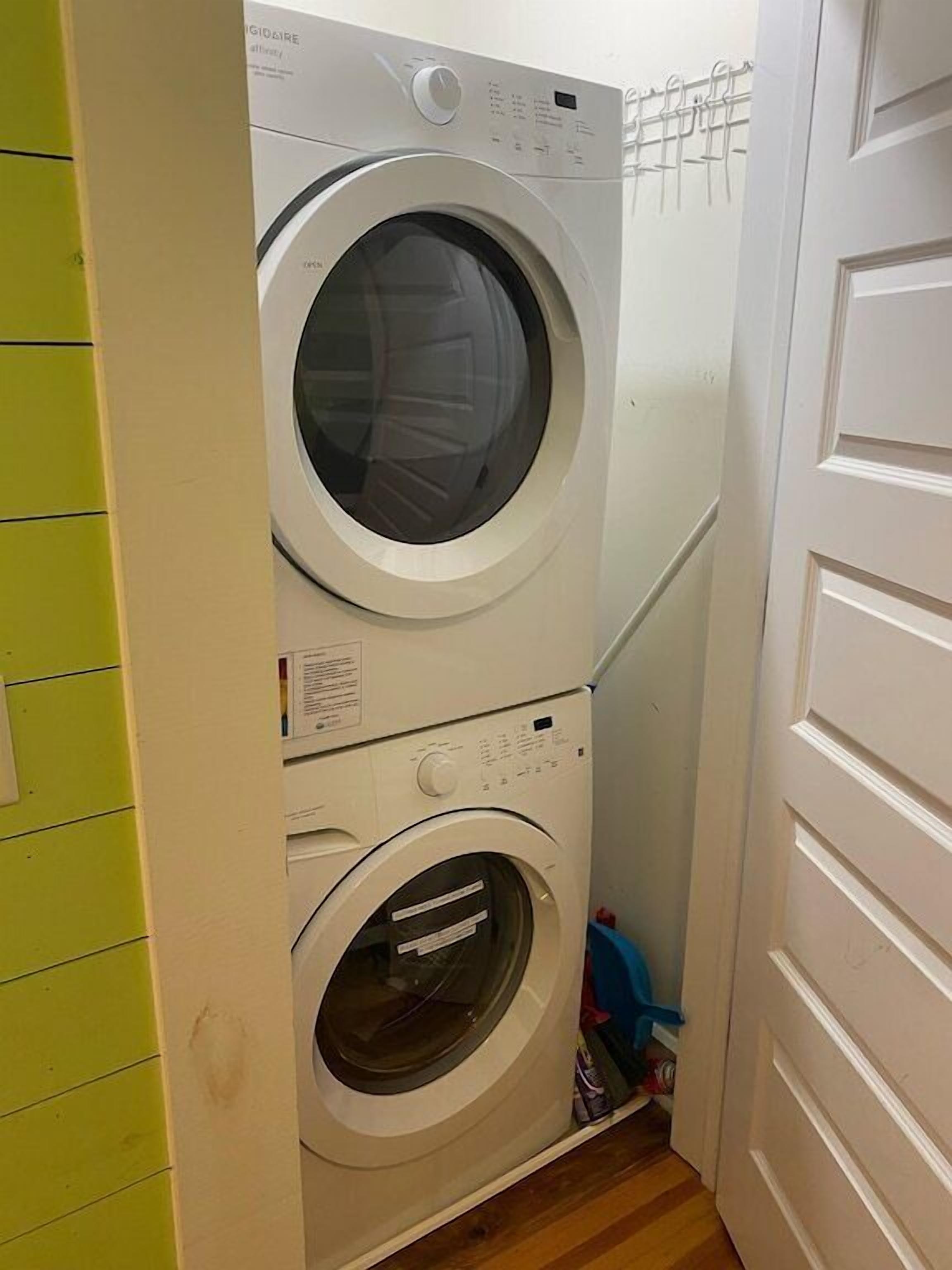 A laundry room with two stacked front-loading washing machines and a drying rack.