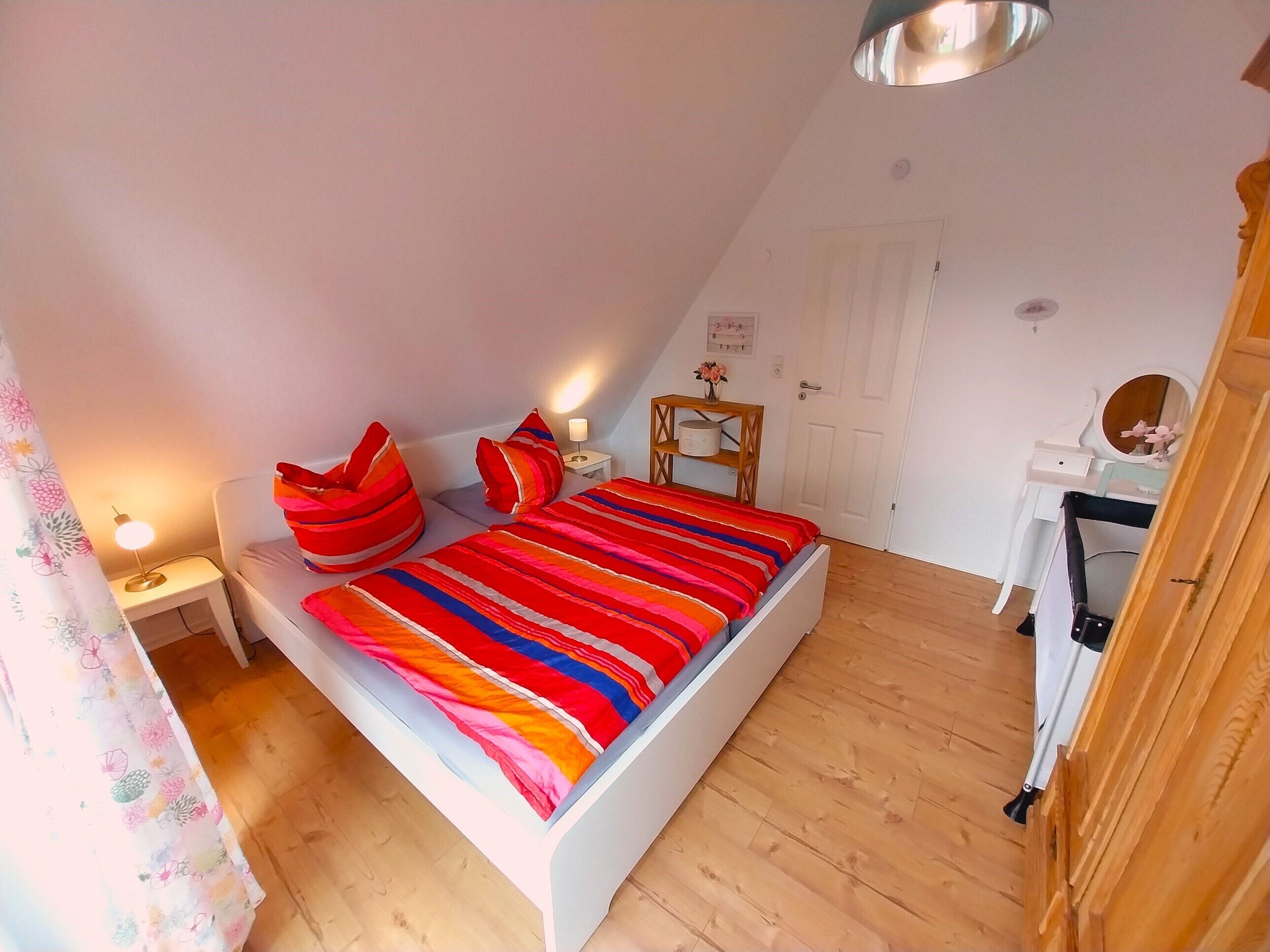 A bedroom with a bed, bedside tables, a dresser, and a door.