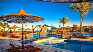 Een zwembadgedeelte met ligbedden, parasols en een waterglijbaan.
