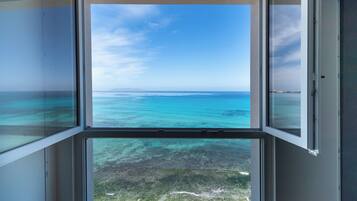 A view through a window with a clear sky and turquoise sea.