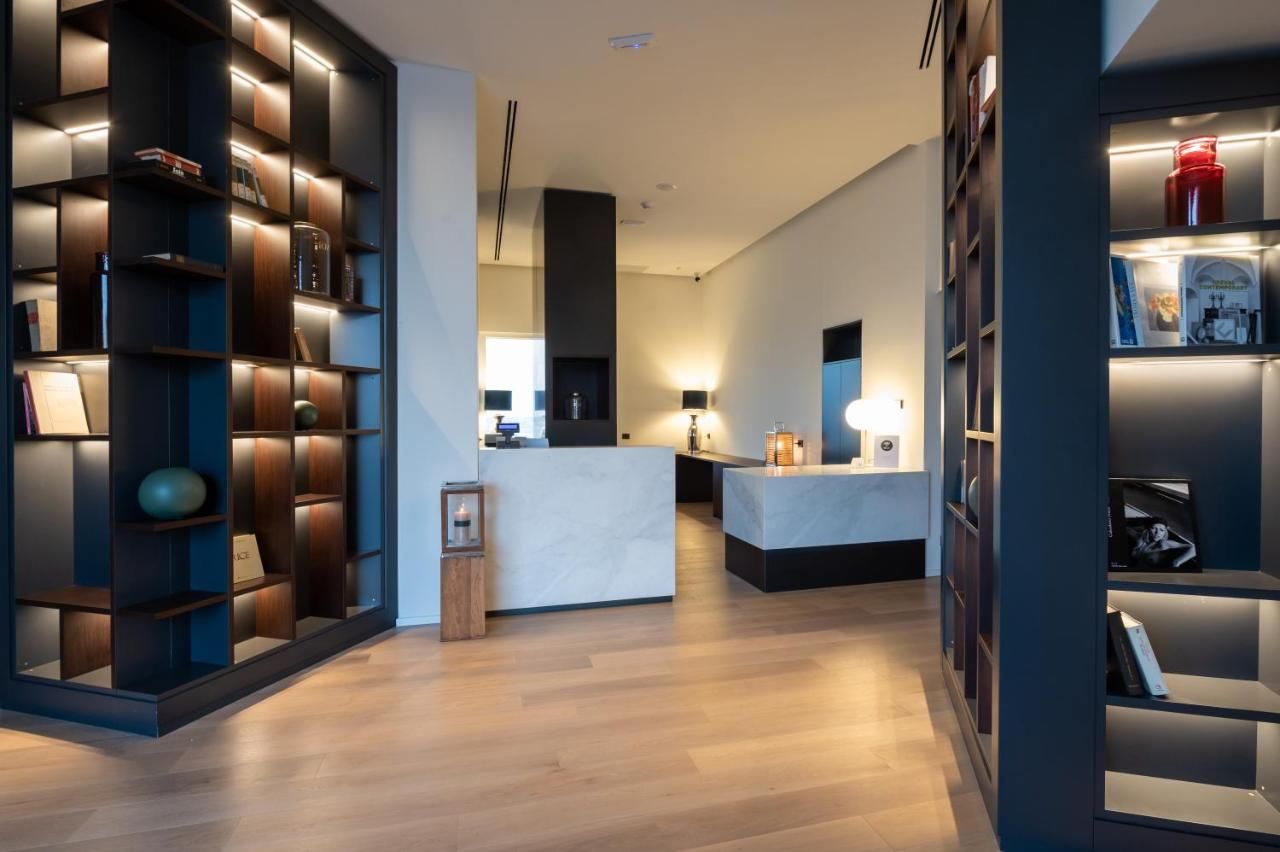 A modern interior with a central reception desk, wooden flooring, and built-in bookshelves with integrated lighting.