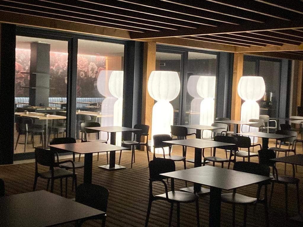 Ett modernt matområde med bord och stolar, stora fönster och en unik lampa.