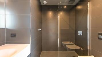 Un baño moderno con ducha de vidrio, inodoro y lavamanos.