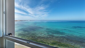 A view from a balcony overlooking a turquoise sea with a clear sky.