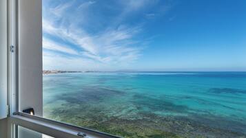 A view from a balcony overlooking a turquoise sea with a clear sky.