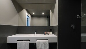 A modern bathroom with a large mirror, a white sink, and two towels hanging on hooks.