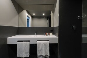 A modern bathroom with a large mirror, a white sink, and two towels hanging on hooks.