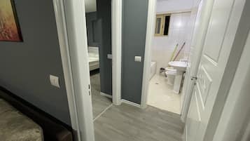 Ein Flur, der zu einem Schlafzimmer mit Bett und einem Badezimmer mit Toilette und Waschbecken führt.