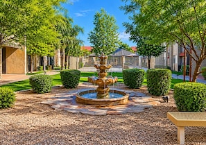 A fountain surrounded by a stone pathway, with neatly trimmed hedges and trees. - Pool & Hot Tub | Multi-Streaming | By Airport, ASU (Tempe)