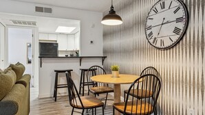 Una cocina moderna con un reloj grande, una mesa de comedor de madera y sillas negras.