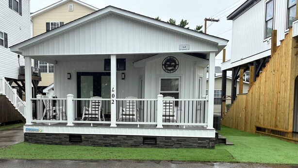 A white single-story house with a porch, a mailbox, and a small front yard. - Shore Beats Work Bungalow (myrtle beach)
