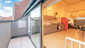 Un apartamento moderno con cocina, comedor y balcón con puerta de vidrio.