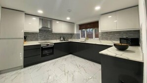 Cozinha moderna com armários brancos, bancada preta e piso de mármore.
