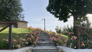 A stone staircase with pink flowers on either side, leading up a grassy hill. - Villa with Pool, Spa, and Relaxation: A Paradise between Umbria and Tuscany (Umbertide)