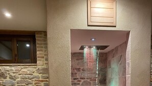 A stone-walled bathroom with a shower area, a wooden-framed window, and two lanterns on the floor. - Villa with Pool, Spa, and Relaxation: A Paradise between Umbria and Tuscany (Umbertide)