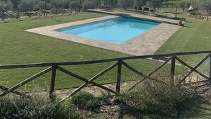 A rectangular swimming pool with a paved deck, surrounded by a wooden fence and a grassy area. - Villa with Pool, Spa, and Relaxation: A Paradise between Umbria and Tuscany (Umbertide)