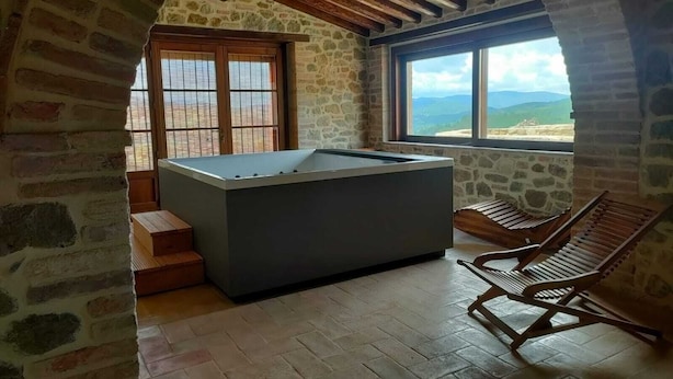 A room with a stone wall, a wooden ceiling, a pool table, and a view of the mountains. - Villa with Pool, Spa, and Relaxation: A Paradise between Umbria and Tuscany (Umbertide)