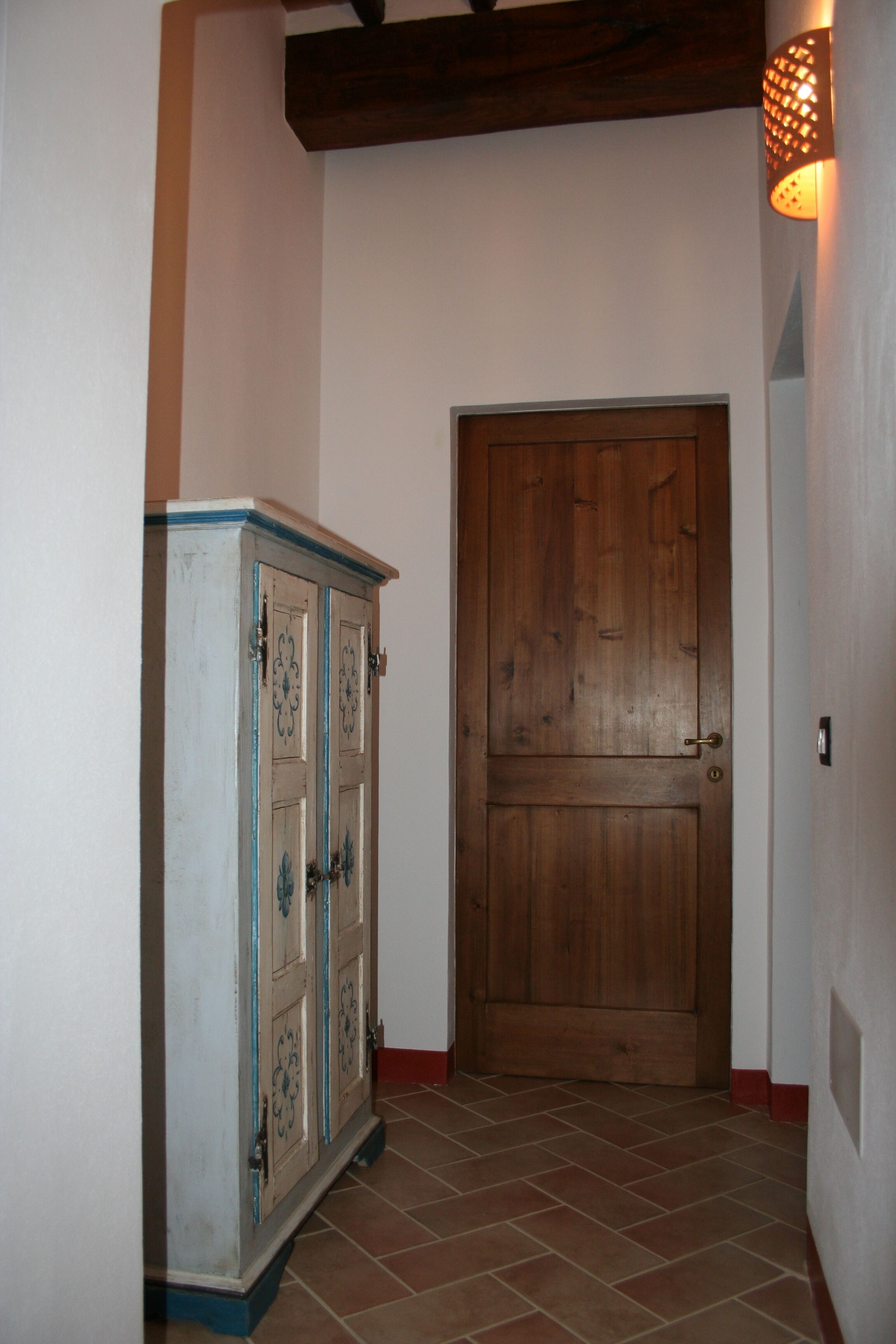 Un couloir avec une porte en bois et un meuble orné de panneaux décoratifs.
