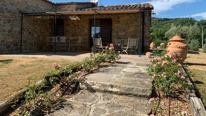 A stone building with a tiled roof, a covered patio with metal chairs, and a stone pathway leading to the entrance. - Villa with Pool, Spa, and Relaxation: A Paradise between Umbria and Tuscany (Umbertide)