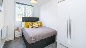 Ein Schlafzimmer mit Bett, Schrank, Nachttisch und Fenster.