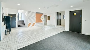Eine geräumige Lobby mit gefliestem Boden, einer Treppe und einer Tür mit einem Warnschild.