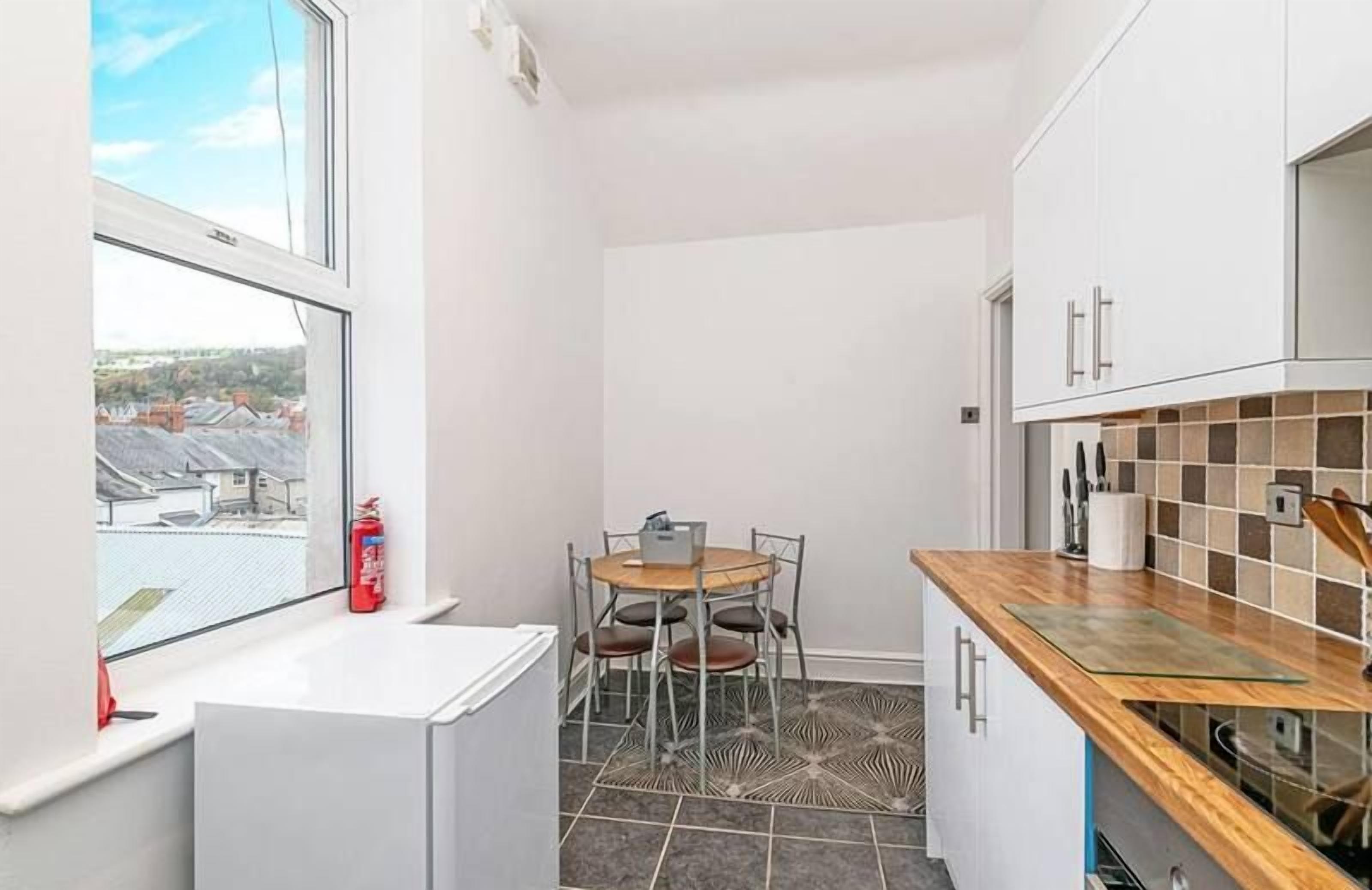 A compact kitchen with a dining table, a window with a view, and a tiled floor.