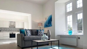 Un salon moderne avec un canapé gris, une table basse et un tapis bleu.