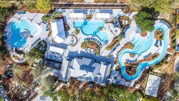 Vista aérea de un complejo turístico con múltiples piscinas, incluyendo una piscina central grande y piscinas más pequeñas conectadas por senderos.