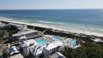 A resort with multiple buildings, a large pool area, and a beach view.
