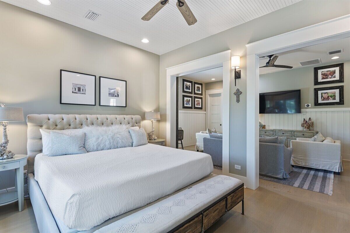 A bedroom with a large bed, a bedside table, a lamp, and a ceiling fan.