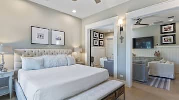 A bedroom with a large bed, a bedside table, a lamp, and a ceiling fan.