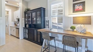 Una cocina con una isla de madera, armarios blancos y un mueble negro con puertas de vidrio.