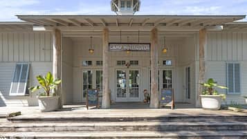 A building with a sign reading 'Camp Watercolor' and a covered entrance with steps leading up to it.