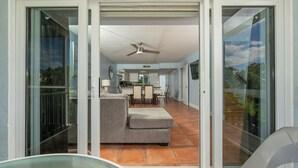A modern living room with a sofa, a dining area with chairs, a ceiling fan, and a kitchen in the background. - Amazing Key Largo Tropical Paradise 3/3 Townhouse with Water Lagoon view (Key Largo)