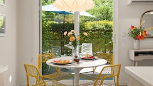 A dining area with a round table, yellow chairs, a white tablecloth, a vase with flowers, and a hanging light fixture. - DreamCatcher-S Uptown! Walk to Shop/Dine/Hike (Sedona)