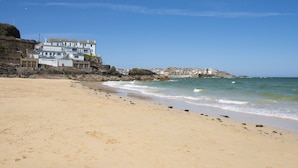 Uma praia com um edifício grande à esquerda, com várias varandas e uma base de pedra.