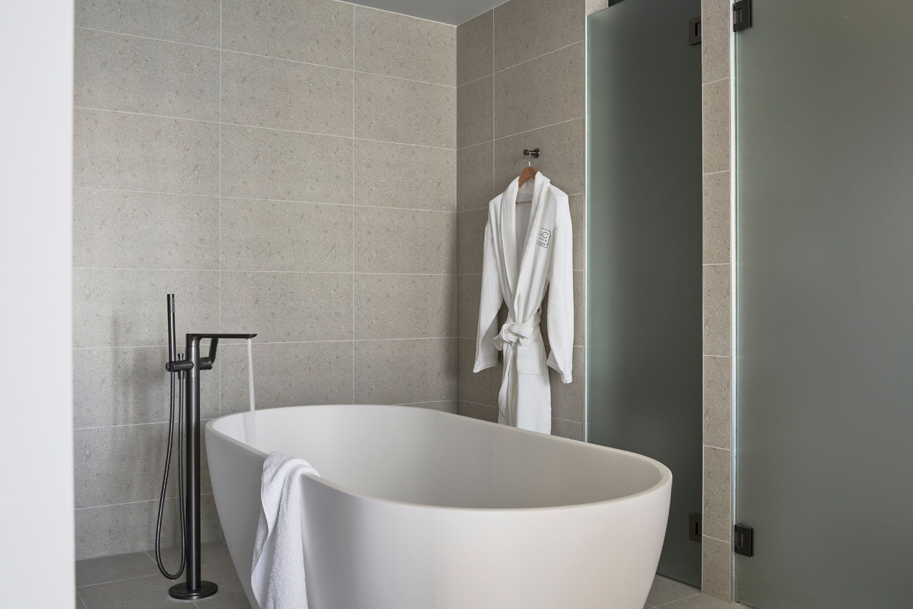 Un baño moderno con una bañera independiente, un perchero y un cabezal de ducha.