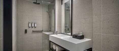 A modern bathroom with a large mirror, a white sink, and a shower area.