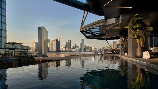 Una piscina interior con vista al horizonte de la ciudad, arquitectura moderna y plantas en macetas.