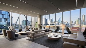 Un salón moderno con vista a la ciudad, con sofás, sillones y una mesa de centro.
