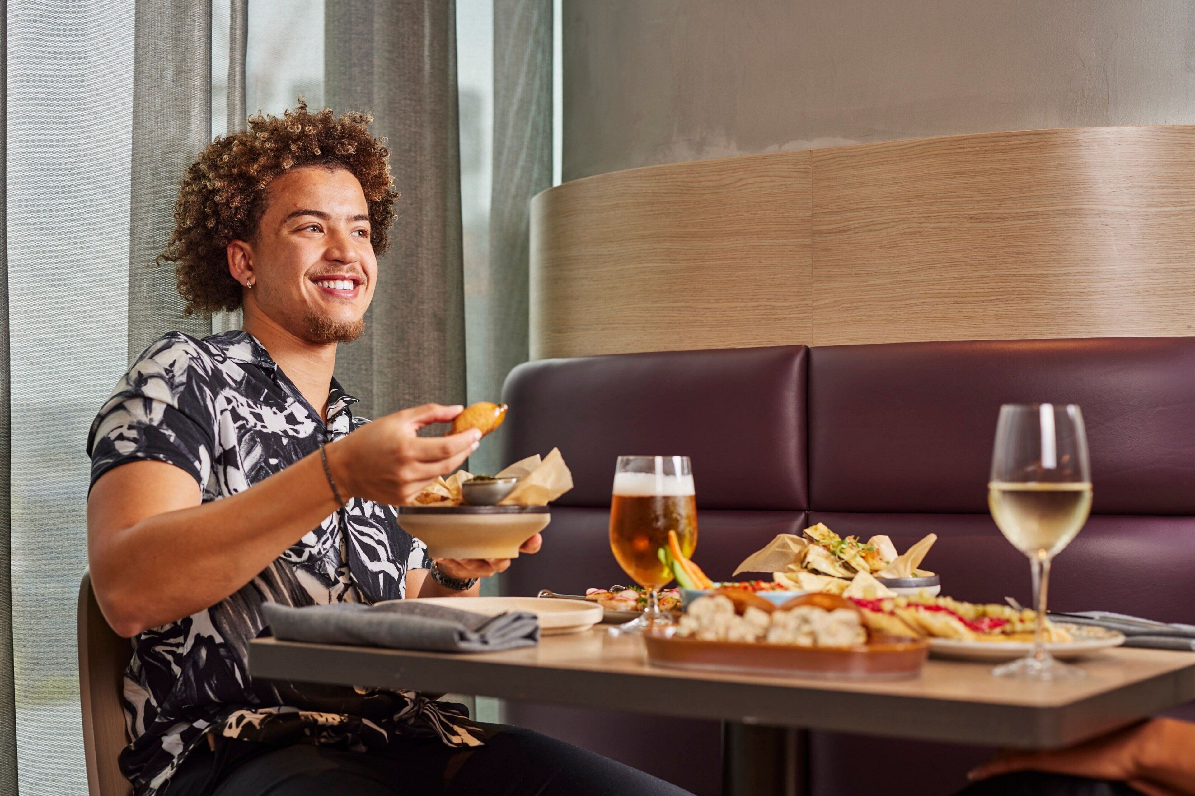 A person dining at a table with a variety of dishes and drinks.