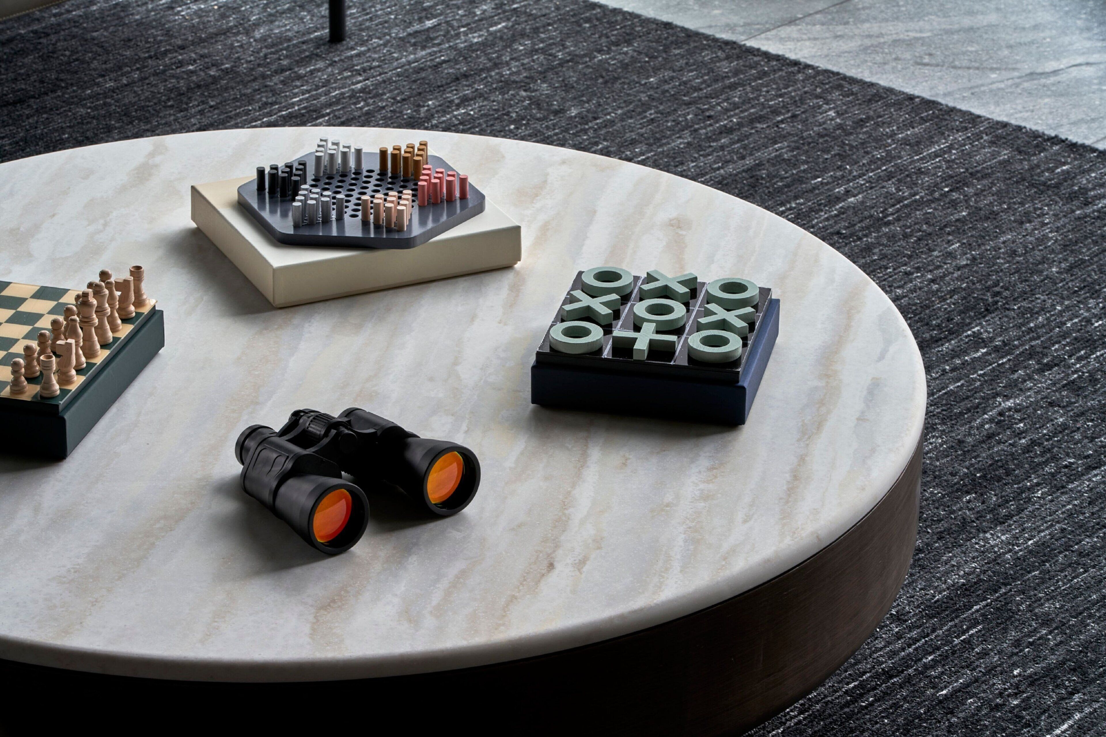 A round marble table with chess sets and binoculars.